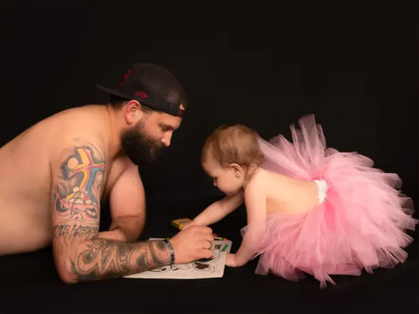 Dad and little daughter together wearing princess dresses for a photo